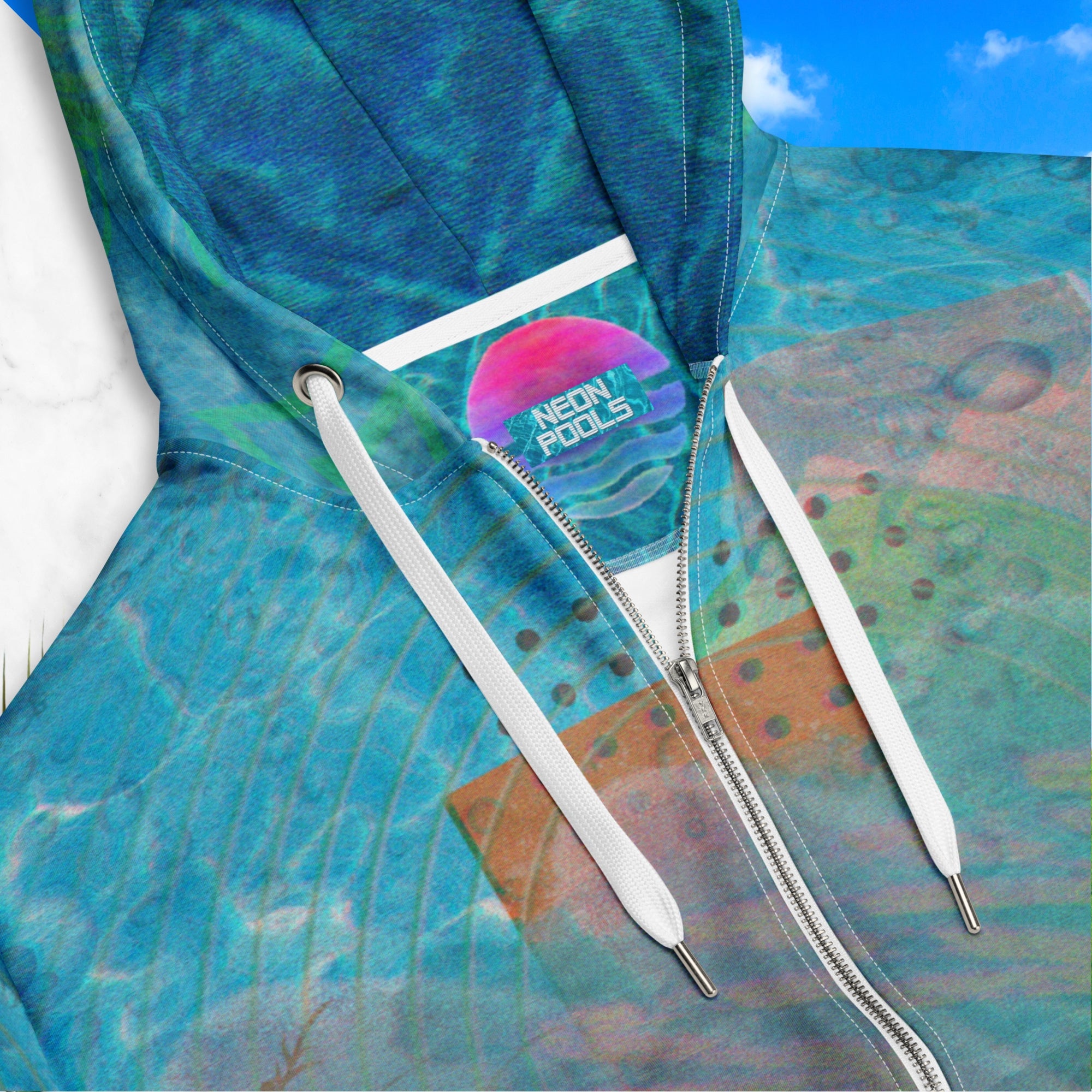 Closeup neck line and inner label patch with Neon Pools insignia on full color all over print zip hoodie with 90s retro abstract squiggles and blurred concentric rings on top of abstract shapes on top of tropical plants and rocks on top of blue pool water with a VHS distortion blur effect with Memphis design abstract shapes on the seams and hood