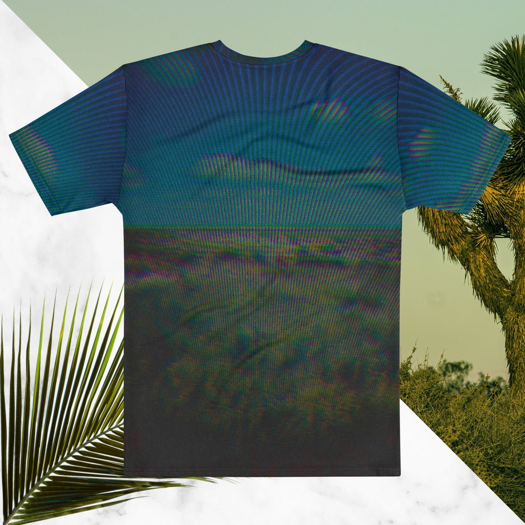 Full color all over print graphic tee shirt with image of a desert and green desert plants and blue sky with clouds above the horizon overlayed with rgb distortion and psychedelic lines graphics fanning outward towards the top