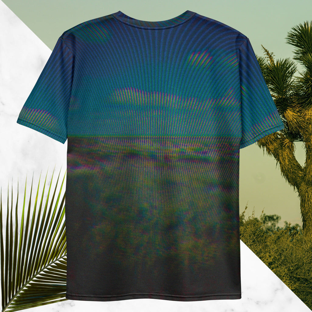 Full color all over print graphic tee shirt with image of a desert and green desert plants and blue sky with clouds above the horizon overlayed with rgb distortion and psychedelic lines graphics fanning outward towards the top