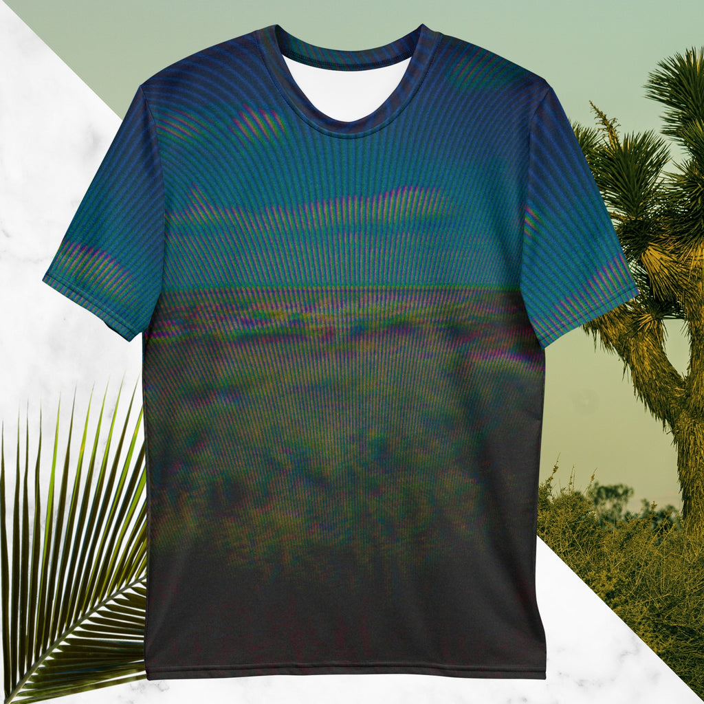 Full color all over print graphic tee shirt with image of a desert and green desert plants and blue sky with clouds above the horizon overlayed with rgb distortion and psychedelic lines graphics fanning outward towards the top