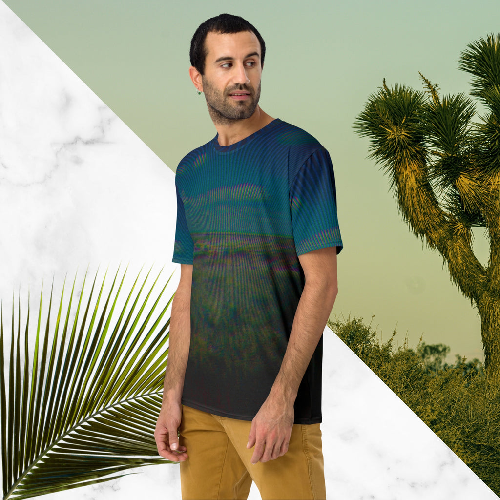 Full color all over print graphic tee shirt with image of a desert and green desert plants and blue sky with clouds above the horizon overlayed with rgb distortion and psychedelic lines graphics fanning outward towards the top