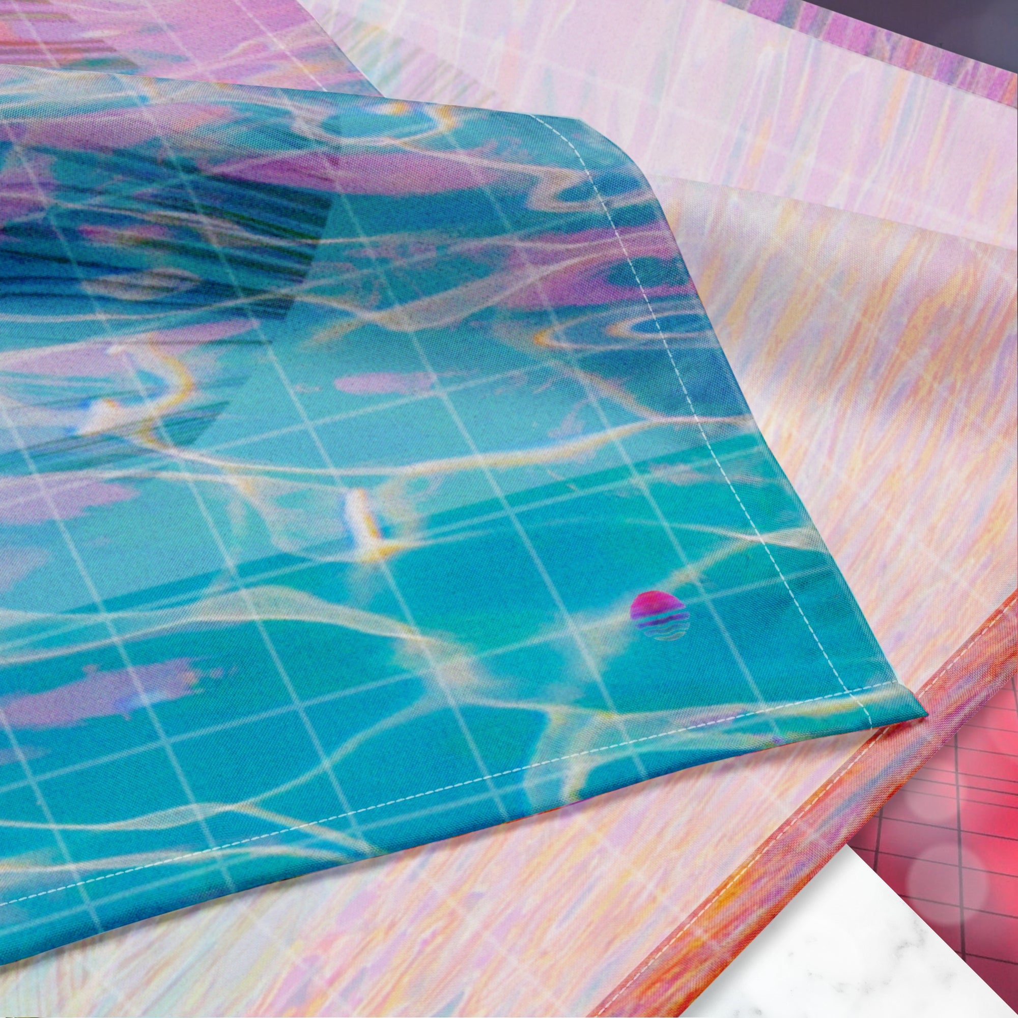 Closeup of Neon Pools logo on corner of full color all over print track jacket depicting blue water reflecting the colors of the sunset in oranges and pinks intensifying towards the top overlayed with a transparent thin white grid with tropical plant silhouettes of tropical plants creating stripe effects on sleeves with Neon Pools vaporwave sun emblem on left chest area