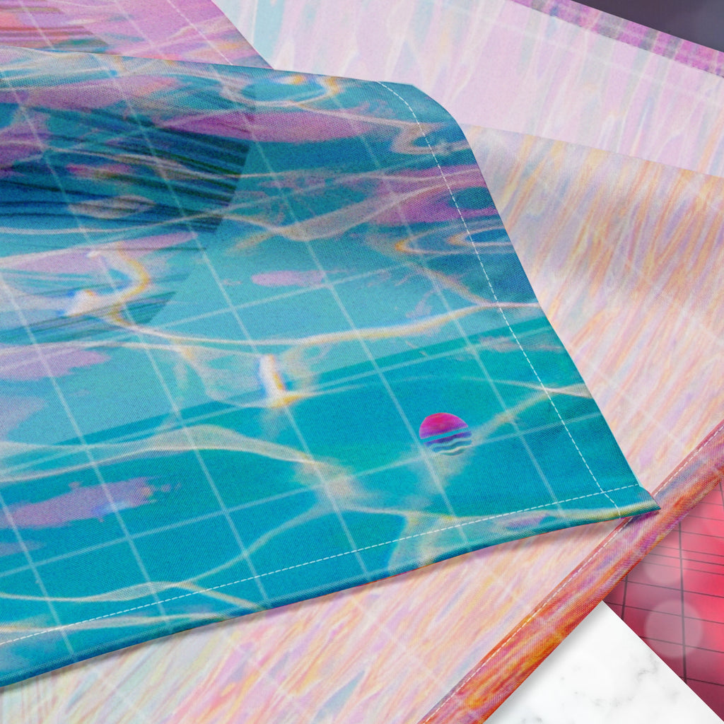 Closeup of Neon Pools logo on corner of full color all over print track jacket depicting blue water reflecting the colors of the sunset in oranges and pinks intensifying towards the top overlayed with a transparent thin white grid with tropical plant silhouettes of tropical plants creating stripe effects on sleeves with Neon Pools vaporwave sun emblem on left chest area