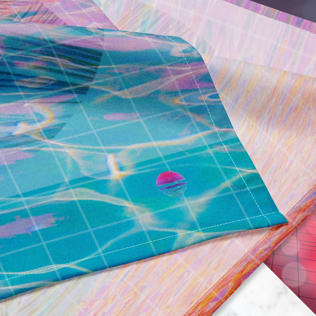 Closeup of Neon Pools logo on corner of full color all over print track jacket depicting blue water reflecting the colors of the sunset in oranges and pinks intensifying towards the top overlayed with a transparent thin white grid with tropical plant silhouettes of tropical plants creating stripe effects on sleeves with Neon Pools vaporwave sun emblem on left chest area