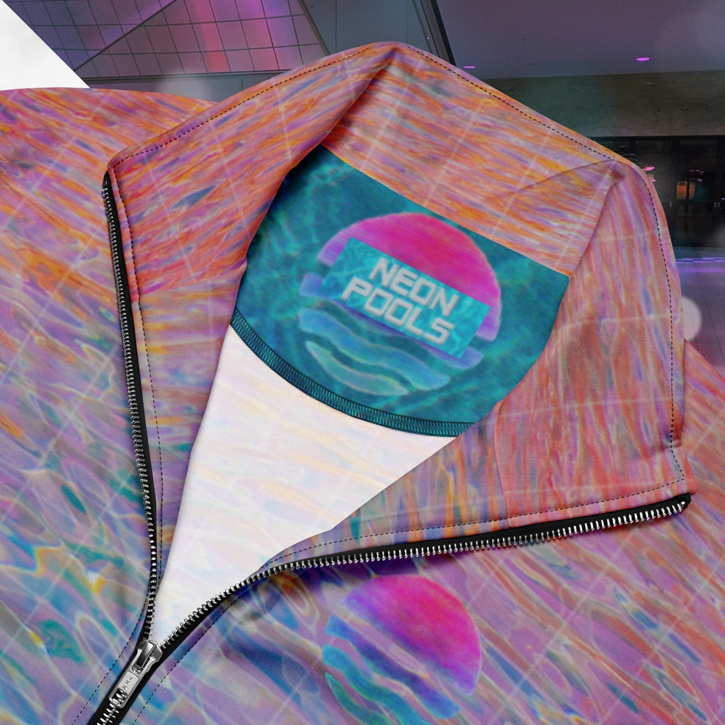 Closeup of neckline and Neon Pools inner logo and insignia on multicolored all over print track jacket depicting blue water reflecting the colors of the sunset in oranges and pinks intensifying towards the top overlayed with a transparent thin white grid with tropical plant silhouettes of tropical plants creating stripe effects on sleeves with Neon Pools vaporwave sun emblem on left chest area