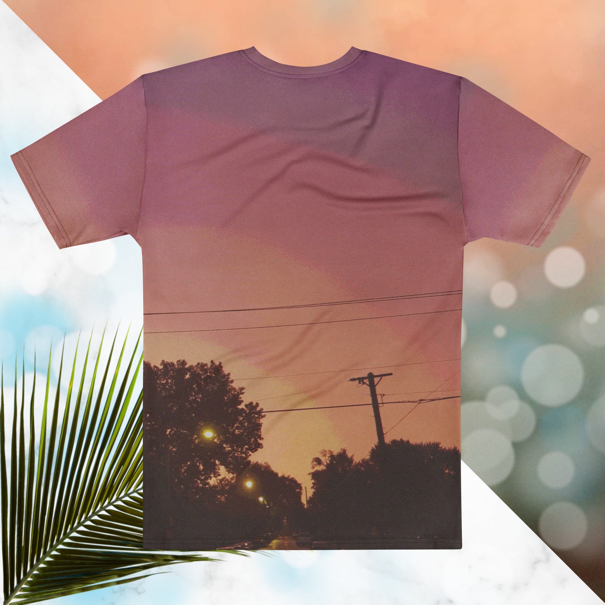 Multicolored all over print graphic t-shirt depicting a sunset with concentric layers of purple, red, orange and yellow with a foreground of trees, street lights, telephone lines and a city street with detailed vhs effects