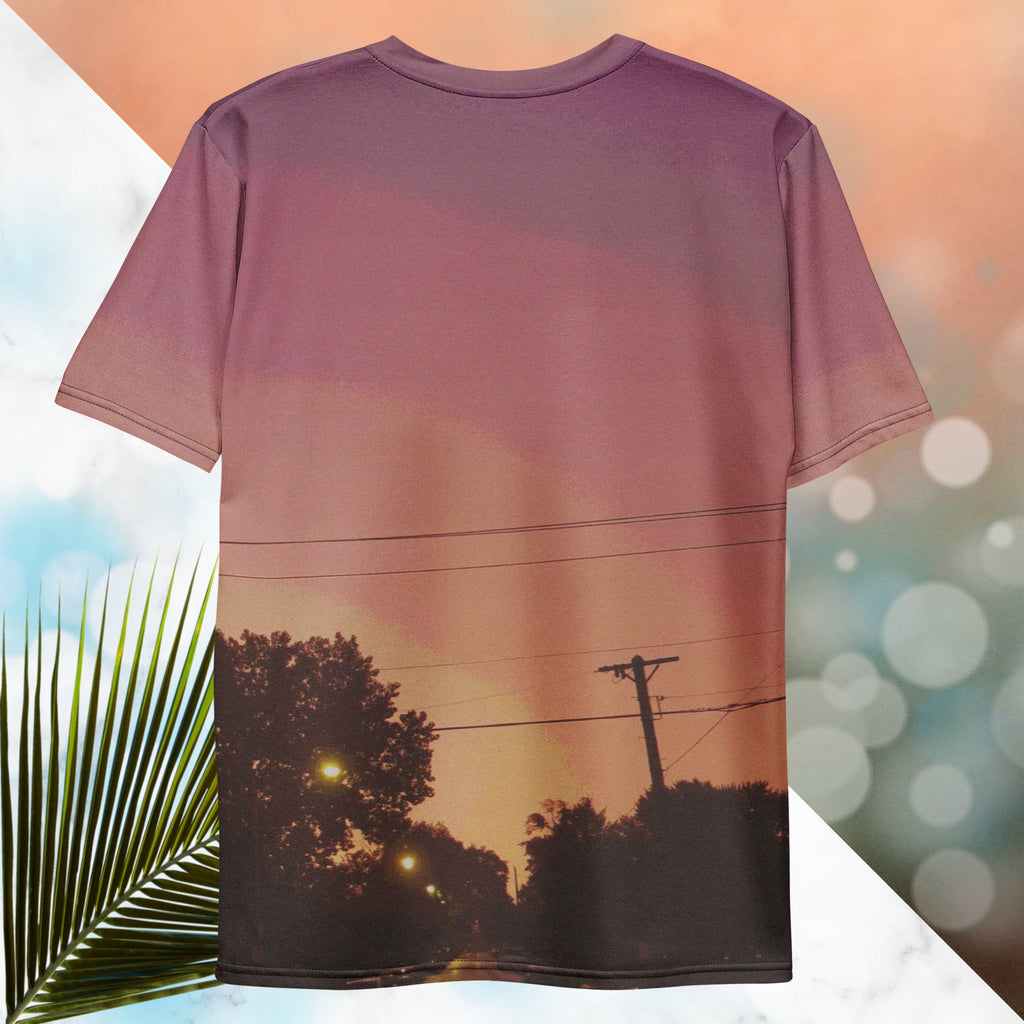 Multicolored all over print graphic t-shirt depicting a sunset with concentric layers of purple, red, orange and yellow with a foreground of trees, street lights, telephone lines and a city street with detailed vhs effects