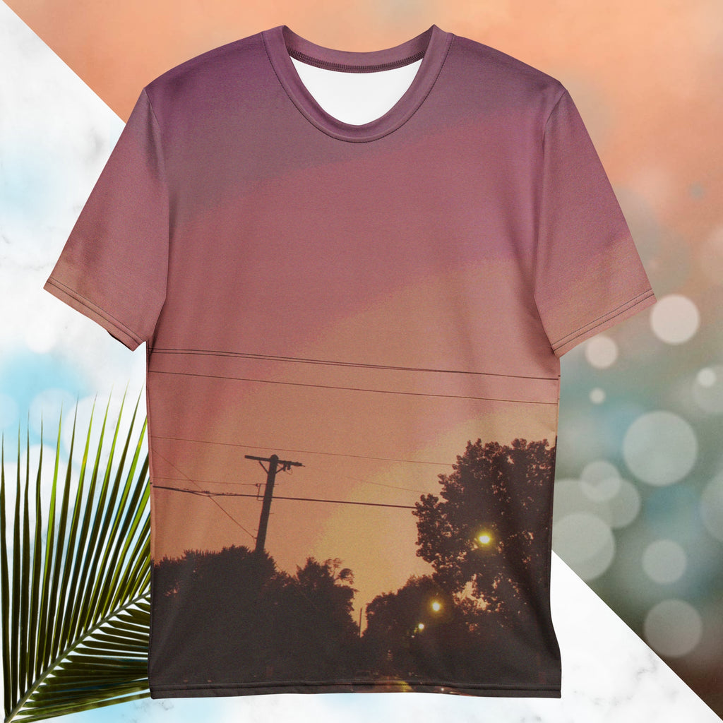 Multicolored all over print graphic t-shirt depicting a sunset with concentric layers of purple, red, orange and yellow with a foreground of trees, street lights, telephone lines and a city street with detailed vhs effects