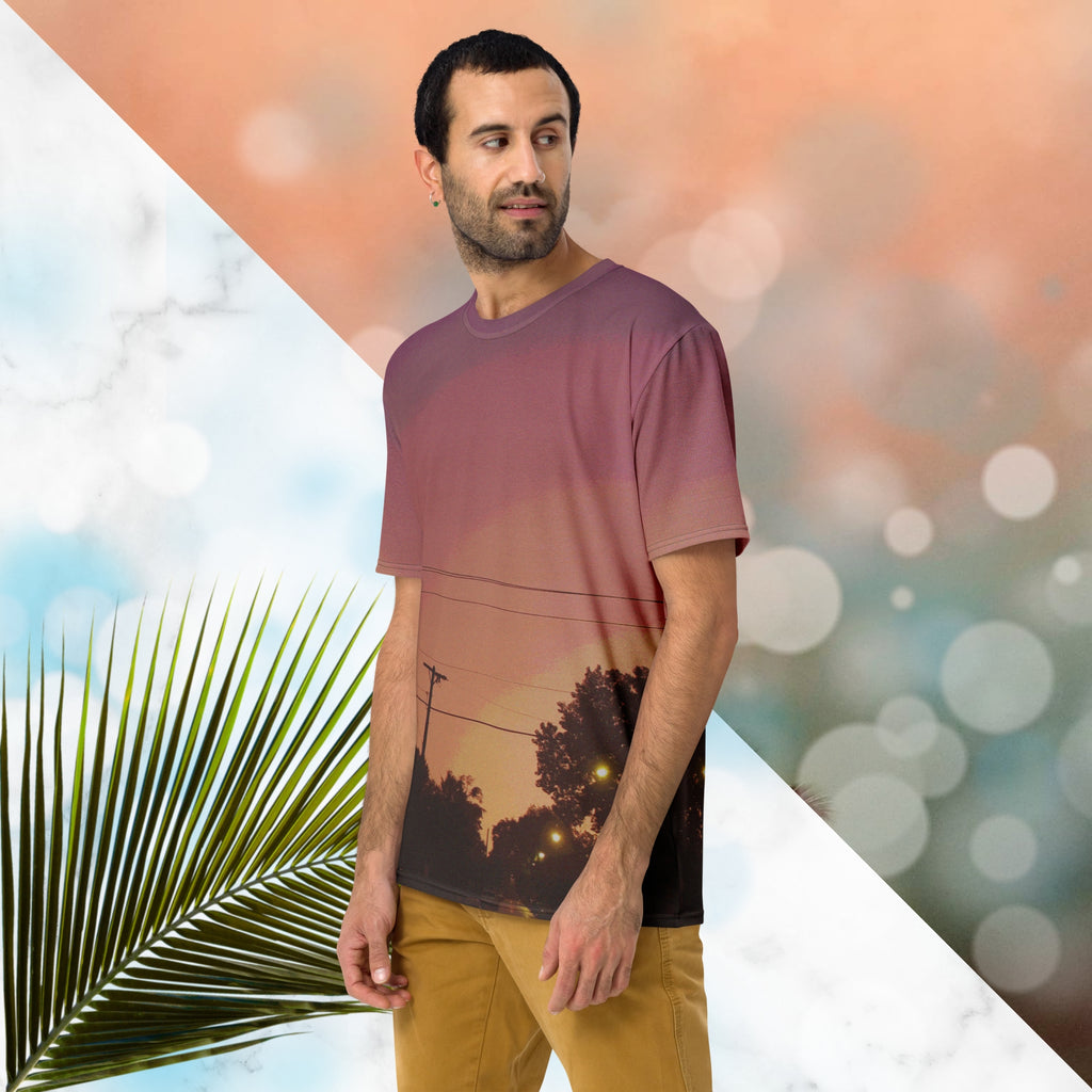 Multicolored all over print graphic t-shirt depicting a sunset with concentric layers of purple, red, orange and yellow with a foreground of trees, street lights, telephone lines and a city street with detailed vhs effects