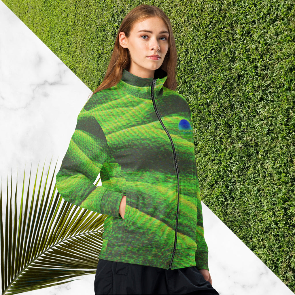 Primarily green and black full color all over print track jacket depicting grass covered green rolling hills and their shadows overlayed with detailed v h s and retro t v distortion with a green and blue Neon Pools vaporwave sun and waves emblem on the left chest