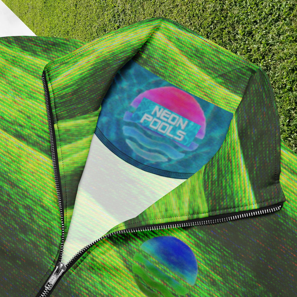 Closeup of neckline and Neon Pools inner logo and insignia on primarily green and black full color all over print track jacket depicting grass covered green rolling hills and their shadows overlayed with detailed v h s and retro t v distortion with a green and blue Neon Pools vaporwave sun and waves emblem on the left chest