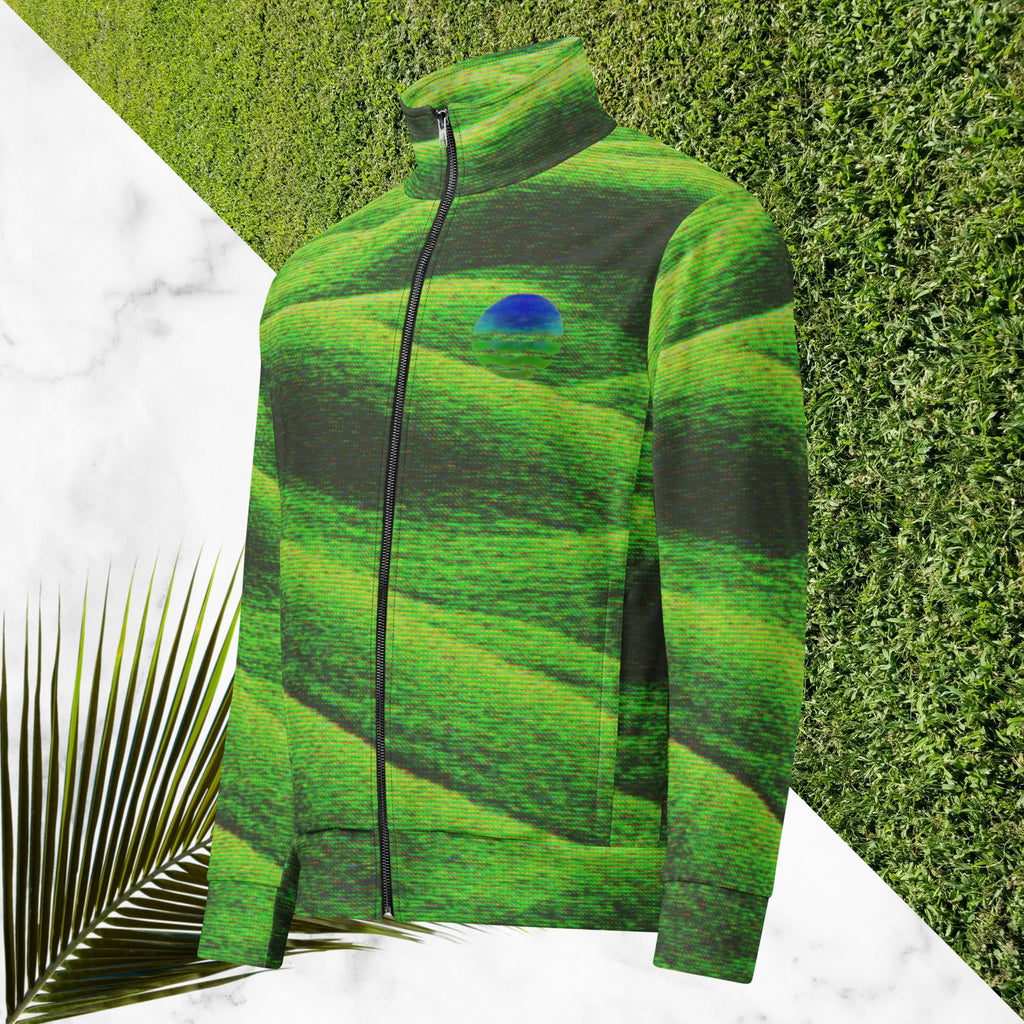 Primarily green and black full color all over print track jacket depicting grass covered green rolling hills and their shadows overlayed with detailed v h s and retro t v distortion with a green and blue Neon Pools vaporwave sun and waves emblem on the left chest