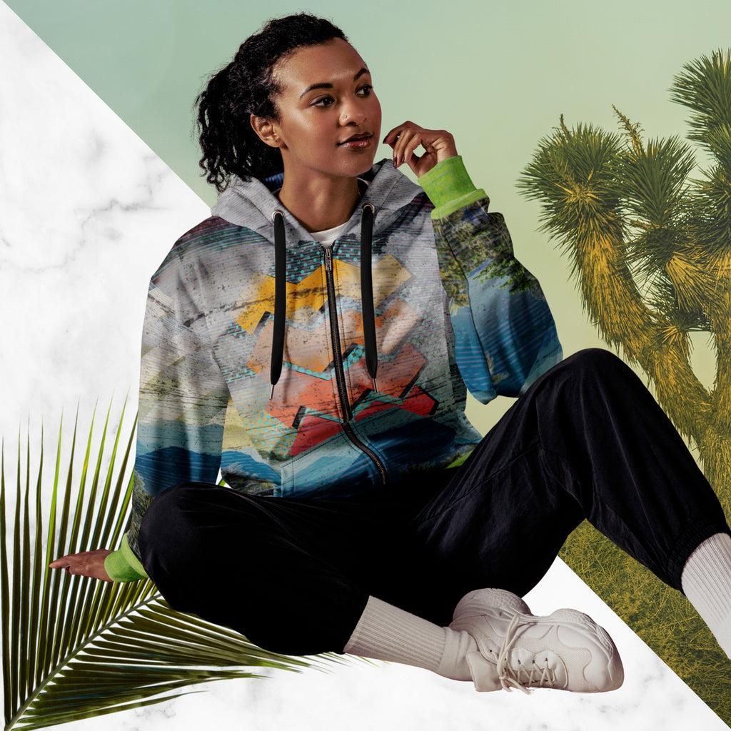 Colorful vaporwave and memphis design inspired all over print zip hoodie depicting a foreground of grass and palm trees with a backdrop of mountains more mountains and a sky filled with retro yellow orange salmon and red cascading bold zigzags tv scan lines turquoise dots and vaporwave broken sun on the back with clouds diagonal white stripes on right sleeve horizontal orange stripes on left sleeve