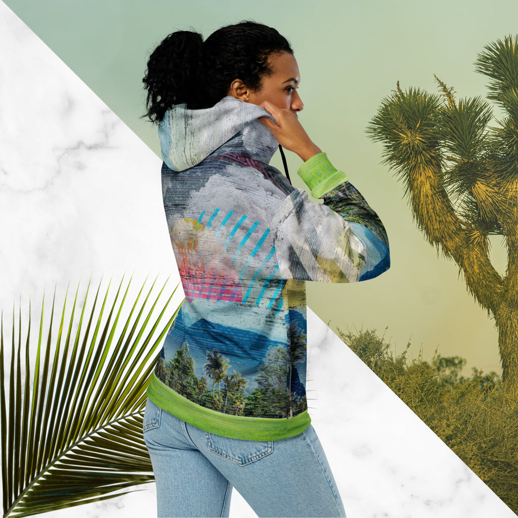 Colorful vaporwave and memphis design inspired all over print zip hoodie depicting a foreground of grass and palm trees with a backdrop of mountains more mountains and a sky filled with retro yellow orange salmon and red cascading bold zigzags tv scan lines turquoise dots and vaporwave broken sun on the back with clouds diagonal white stripes on right sleeve horizontal orange stripes on left sleeve
