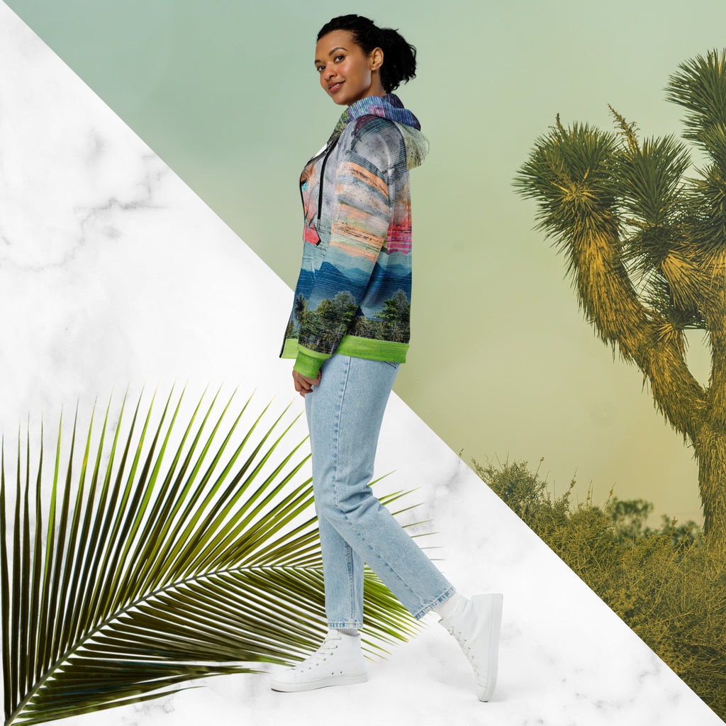 Colorful vaporwave and memphis design inspired all over print zip hoodie depicting a foreground of grass and palm trees with a backdrop of mountains more mountains and a sky filled with retro yellow orange salmon and red cascading bold zigzags tv scan lines turquoise dots and vaporwave broken sun on the back with clouds diagonal white stripes on right sleeve horizontal orange stripes on left sleeve