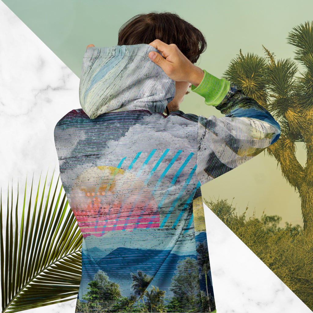 Colorful vaporwave and memphis design inspired all over print zip hoodie depicting a foreground of grass and palm trees with a backdrop of mountains more mountains and a sky filled with retro yellow orange salmon and red cascading bold zigzags tv scan lines turquoise dots and vaporwave broken sun on the back with clouds diagonal white stripes on right sleeve horizontal orange stripes on left sleeve