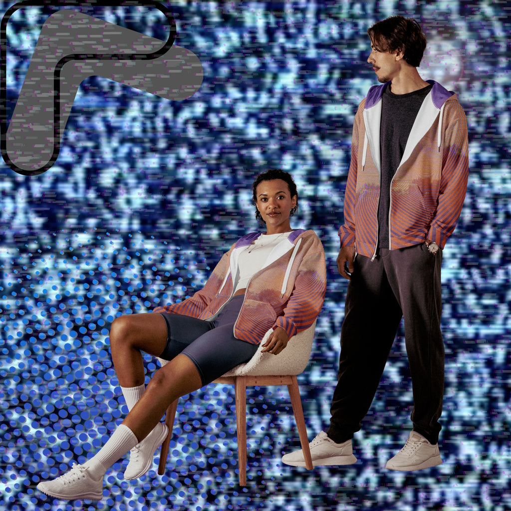 Primarily orange yellow and purple multicolored all over print zip hoodie depicting a treeline with a distorted orange sun in the sky overlayed with a complex orange fractal fanning out from the sun into a solid spiral with detailed v h s distortion and scanlines the spiral creating a stripe effect on the sleeves inner hood is purple sky with scanlines and tv distortion
